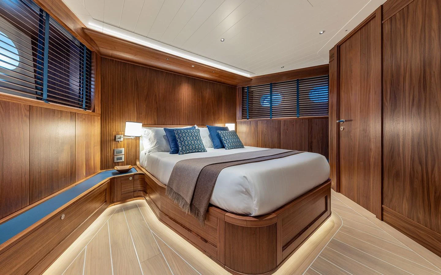 The stateroom features a luxurious bed with elegant wood paneling and ambient lighting. aboard EMPIRE Yacht for Sale