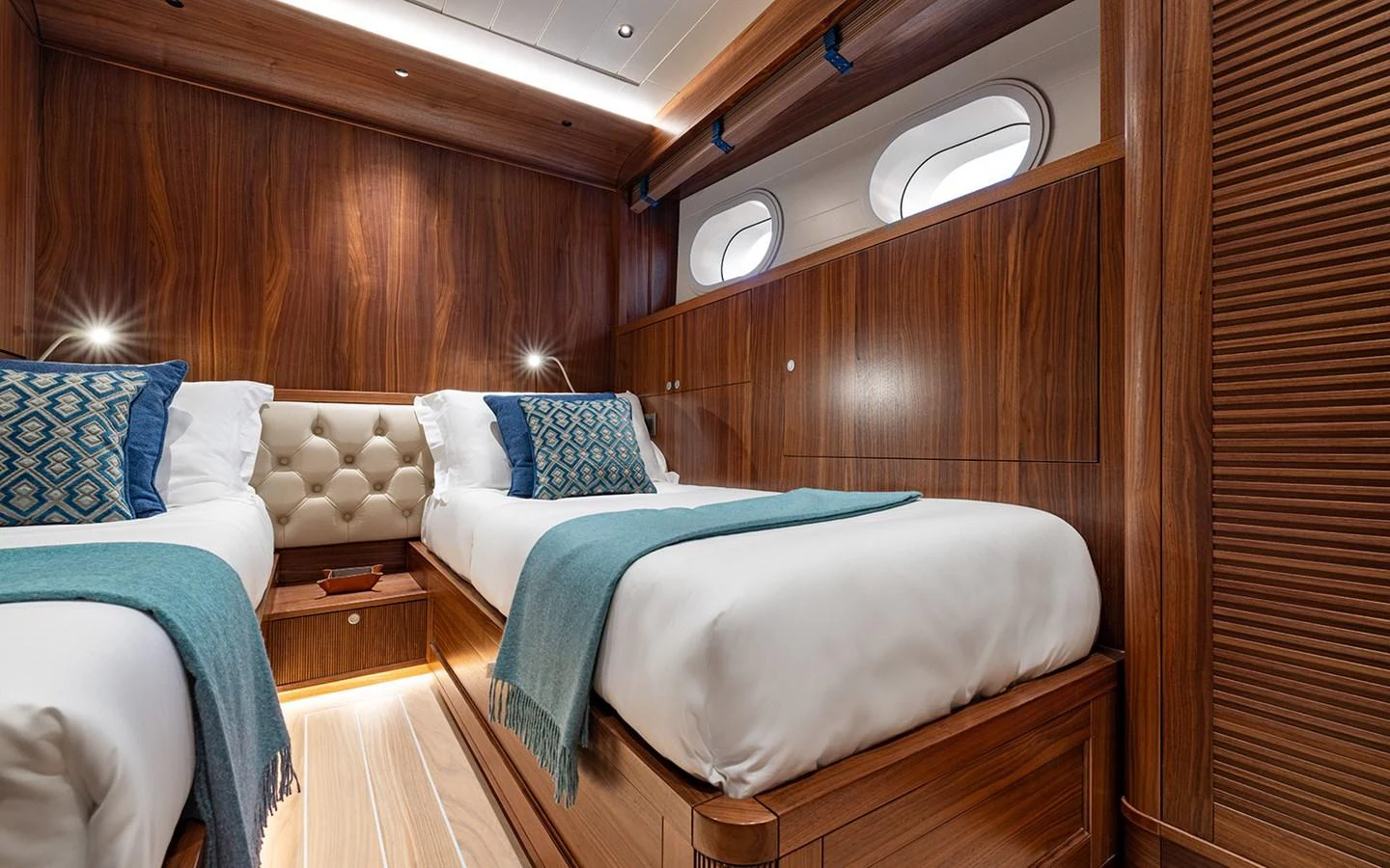 The guest stateroom features twin beds with elegant wood paneling and soft lighting. aboard EMPIRE Yacht for Sale
