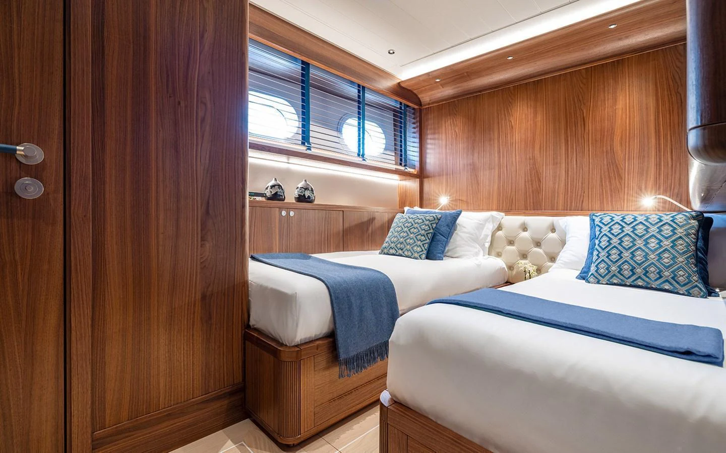 The guest stateroom features twin beds with elegant wood paneling and soft lighting. aboard EMPIRE Yacht for Sale