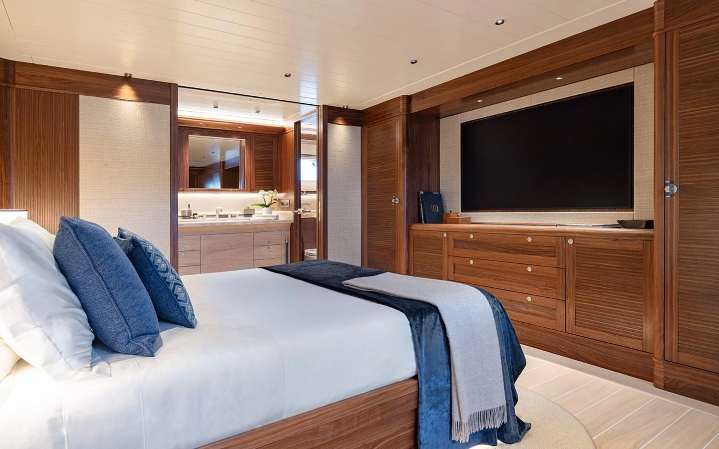 The master stateroom features a luxurious bed, elegant wood finishes, and a large flat-screen TV. aboard EMPIRE Yacht for Sale