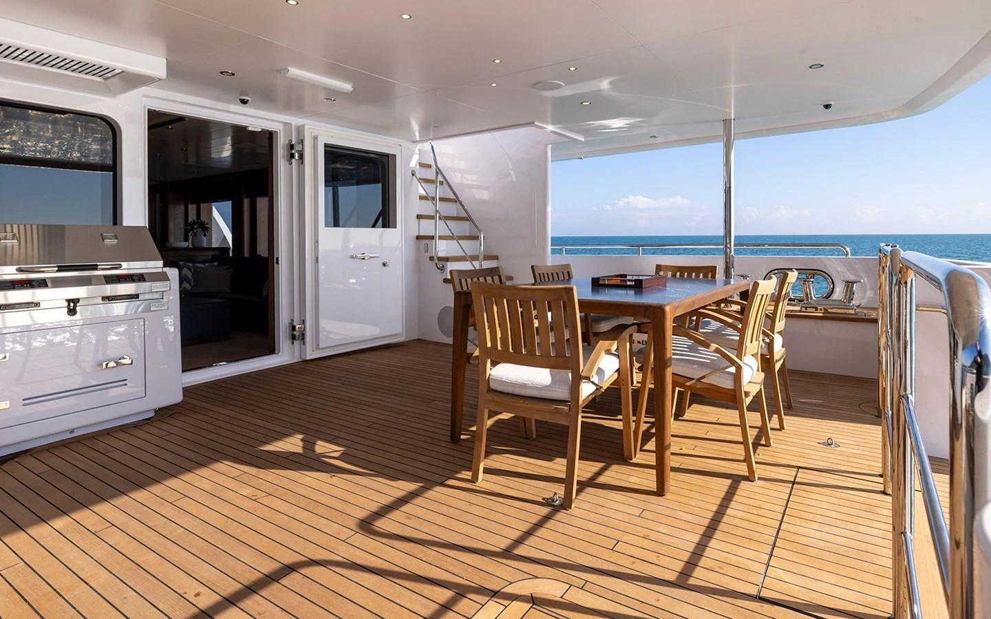 The aft deck features a spacious dining area with wooden furniture and a view of the sea. aboard EMPIRE Yacht for Sale