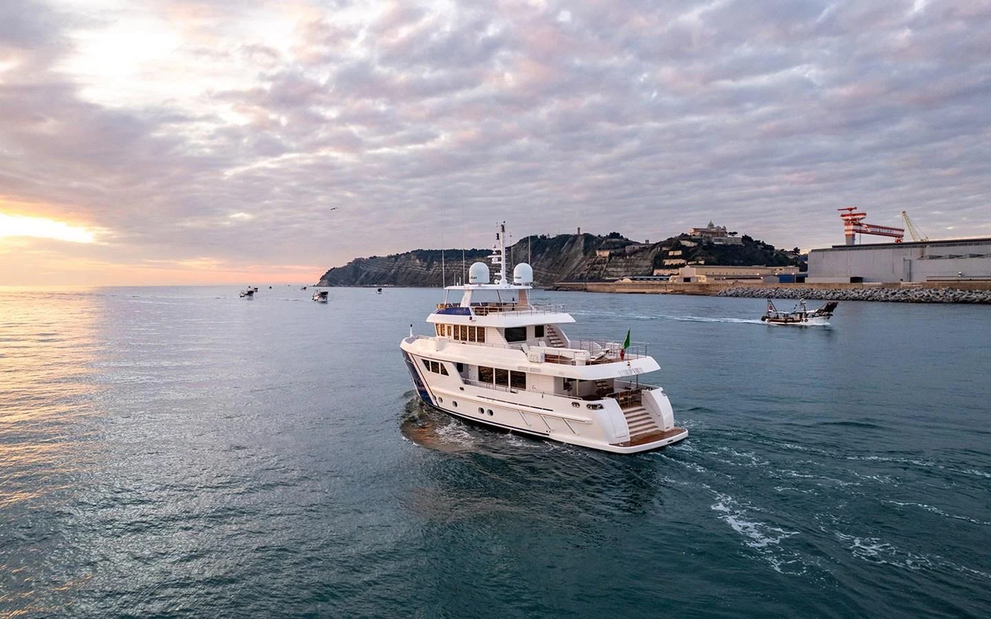 A luxurious yacht cruises gracefully on calm waters with a scenic coastal backdrop. aboard EMPIRE Yacht for Sale