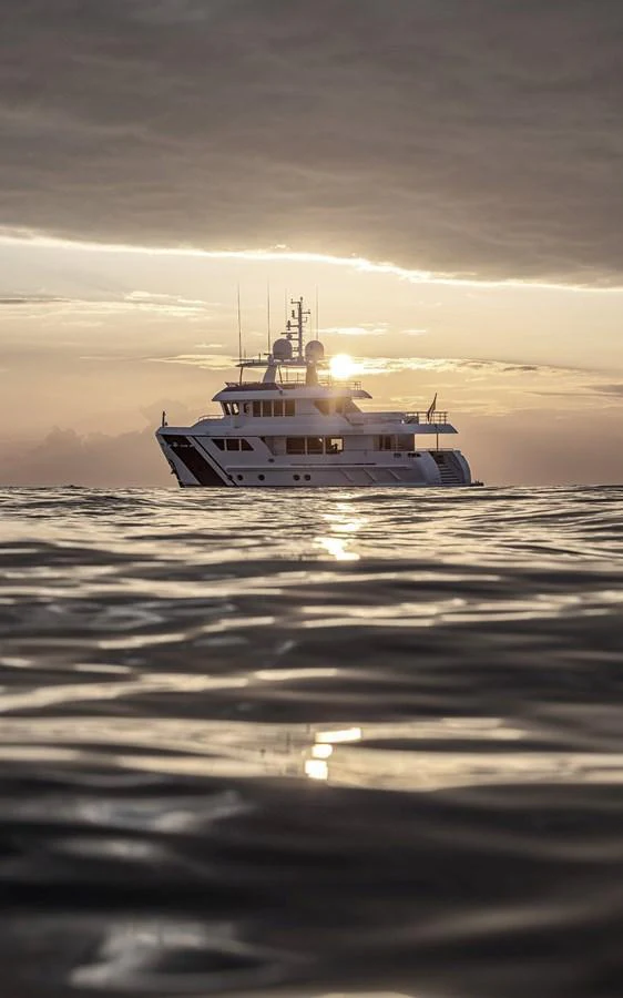 A yacht is seen on the water at sunset, creating a serene and picturesque scene. aboard EMPIRE Yacht for Sale