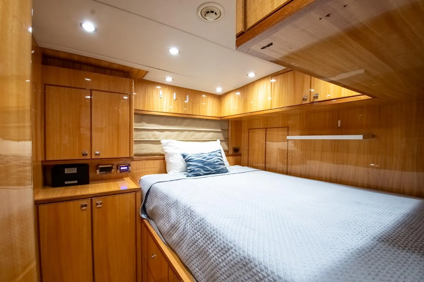 The stateroom features a cozy bed with elegant wooden cabinetry and soft lighting. aboard LUCKY PENNY Yacht for Sale