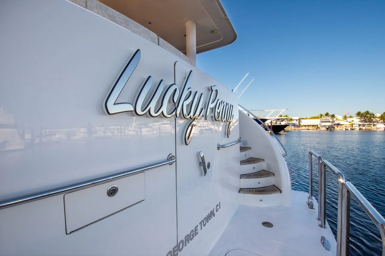 The yacht's name is elegantly displayed on its sleek exterior, with a view of the marina in the background. aboard LUCKY PENNY Yacht for Sale