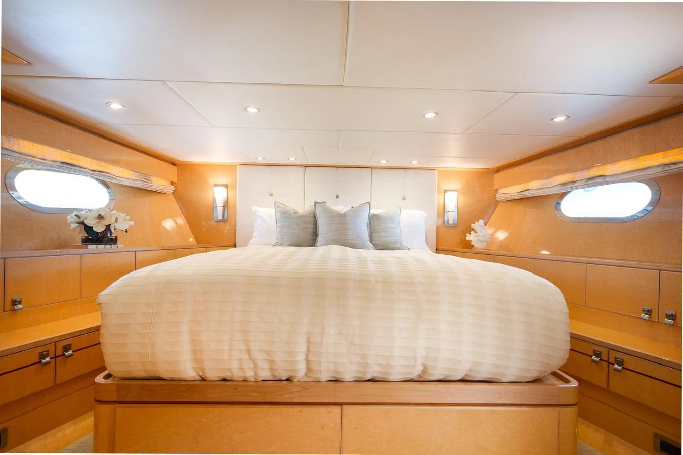 The stateroom features a luxurious bed with elegant lighting and ample natural light from side windows. aboard LUCKY PENNY Yacht for Sale