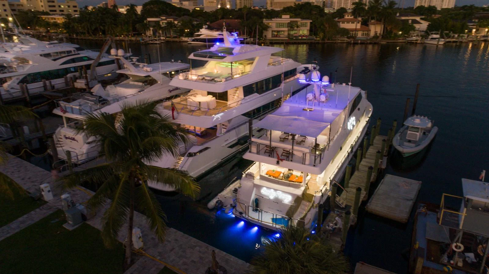 A luxurious yacht is docked at a marina, illuminated beautifully in the evening light. aboard LUCKY PENNY Yacht for Sale