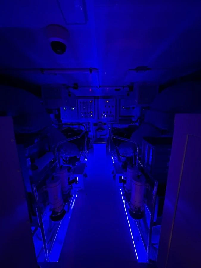 The yacht's engine room is illuminated with blue lighting, showcasing its machinery and control panels. aboard LUCKY PENNY Yacht for Sale