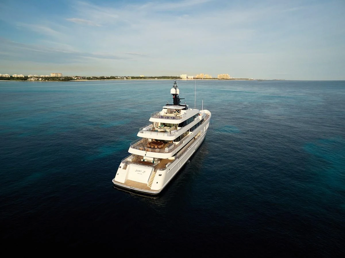 A luxurious yacht cruises through serene blue waters with a distant coastline in view. aboard JUST J'S Yacht for Sale