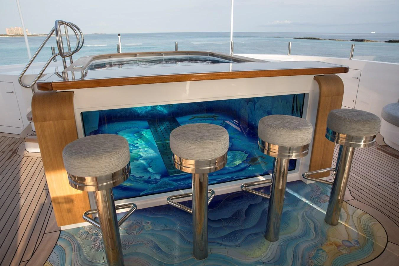 This image showcases a stylish bar area with a unique aquarium feature and comfortable bar stools on the deck of the yacht. aboard JUST J'S Yacht for Sale
