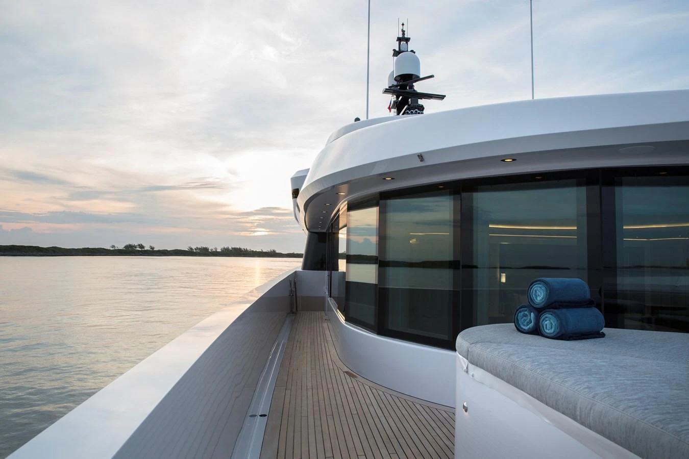 The sleek side deck of the yacht offers a serene view of the water at sunset. aboard JUST J'S Yacht for Sale