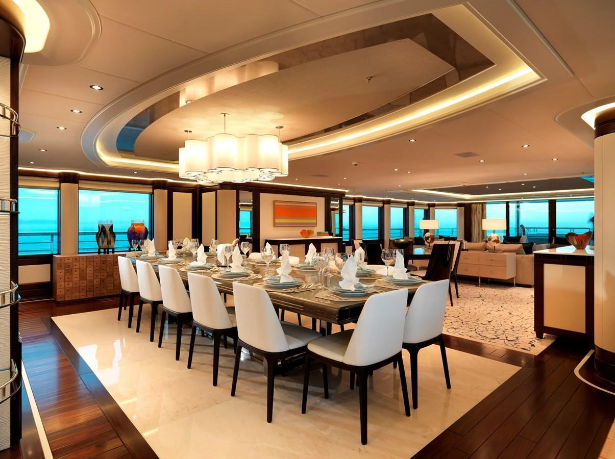 The yacht's dining area features an elegant table set for a formal meal, surrounded by luxurious seating and ambient lighting. aboard JUST J'S Yacht for Sale