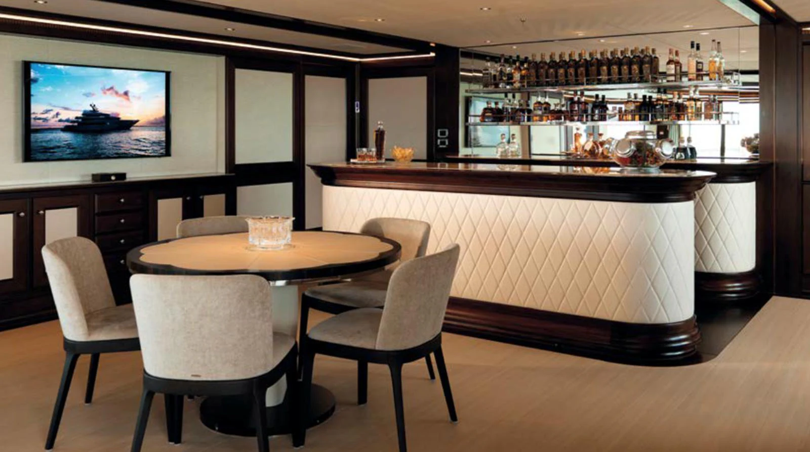 The yacht's interior lounge features a stylish bar and a cozy seating area with a round table and chairs. aboard JUST J'S Yacht for Sale