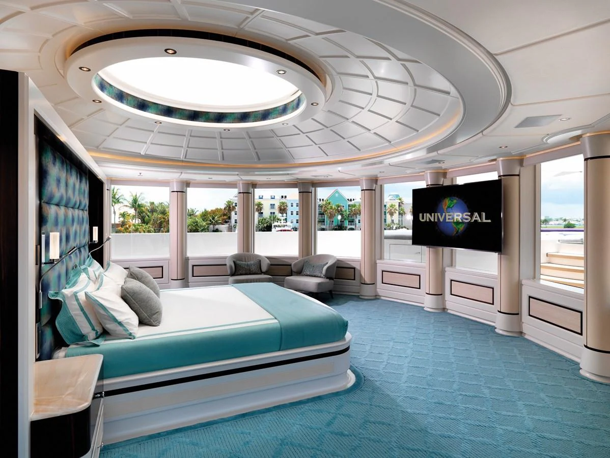 The master stateroom features a luxurious bed, ample seating, and a large television, all bathed in natural light from expansive windows. aboard JUST J'S Yacht for Sale