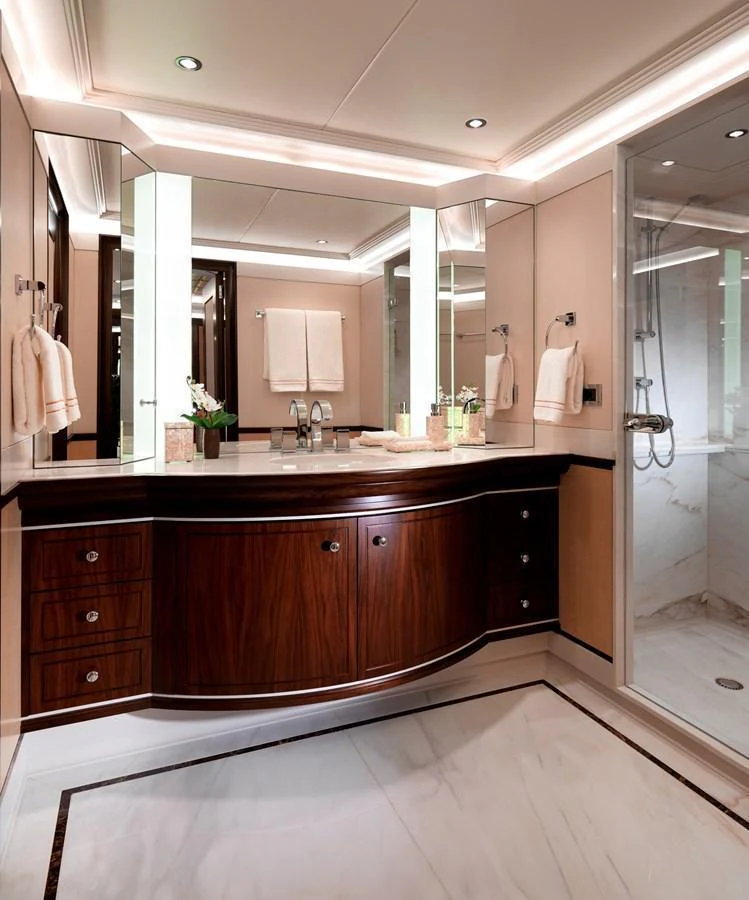 The yacht's bathroom features elegant wood cabinetry, a spacious countertop, and a modern glass-enclosed shower. aboard JUST J'S Yacht for Sale