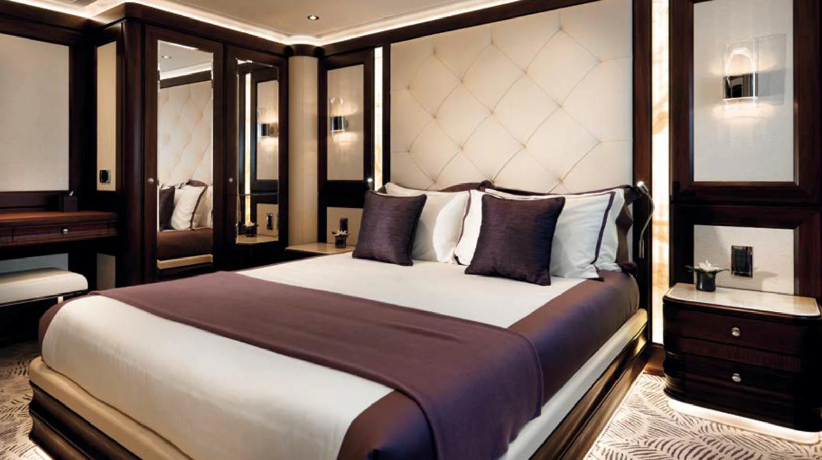 The master stateroom features a luxurious bed with plush pillows and elegant wood finishes. aboard JUST J'S Yacht for Sale