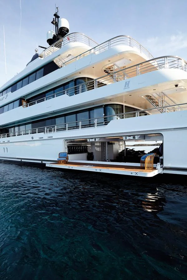 The yacht's exterior showcases multiple decks and an open garage with water toys. aboard JUST J'S Yacht for Sale