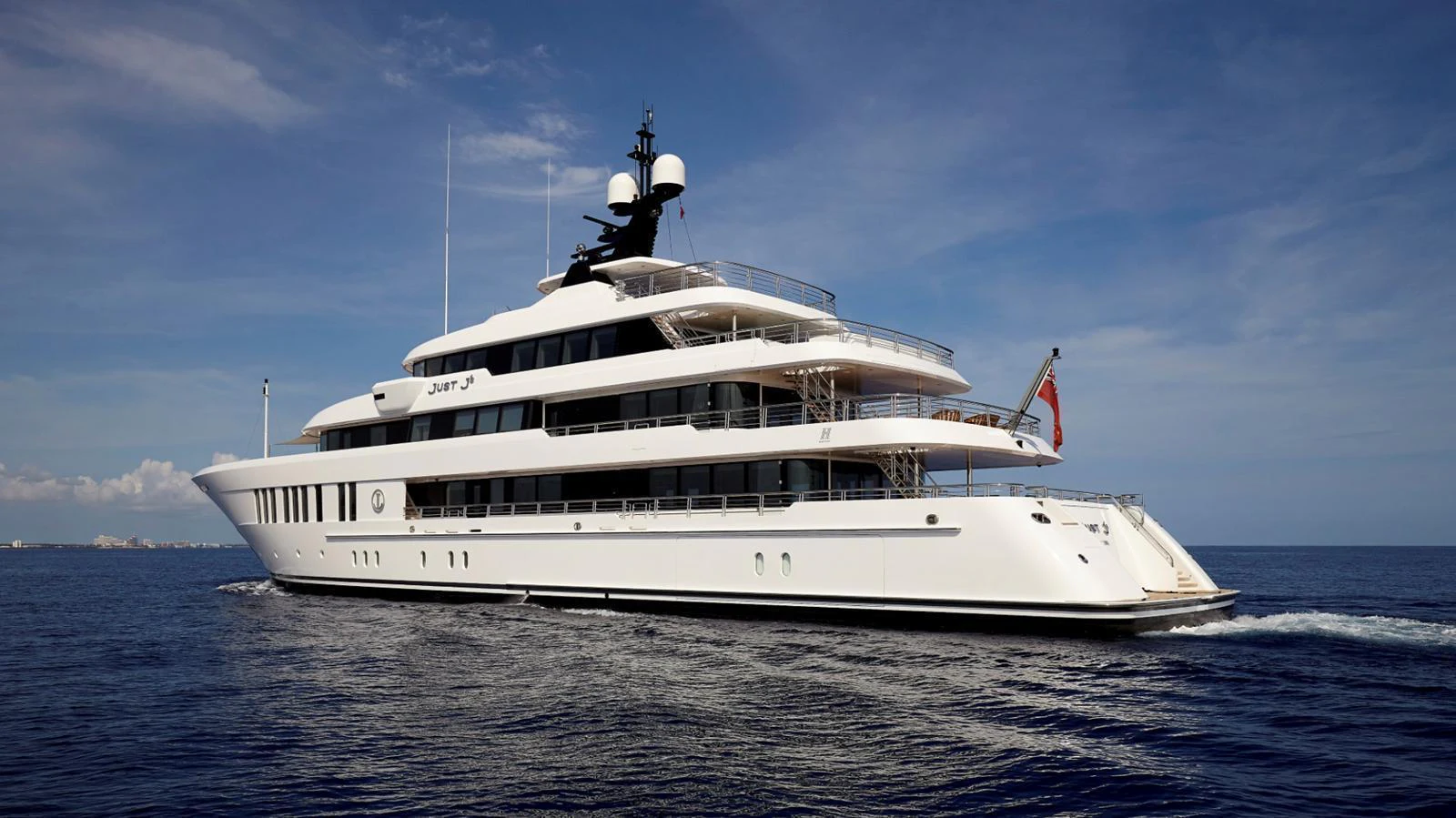 A luxurious yacht glides gracefully on the open sea under a clear blue sky. aboard JUST J'S Yacht for Sale