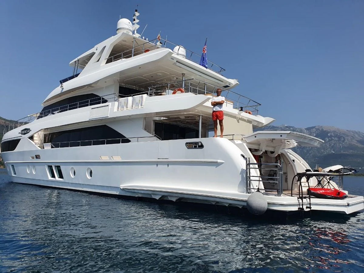 A luxurious yacht is anchored in calm waters, showcasing its multi-level decks and sleek design. aboard AMORE Yacht for Sale