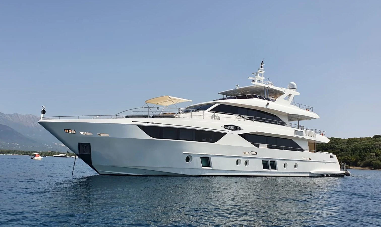 A luxurious yacht is anchored in calm waters, showcasing its sleek design and multiple decks. aboard AMORE Yacht for Sale