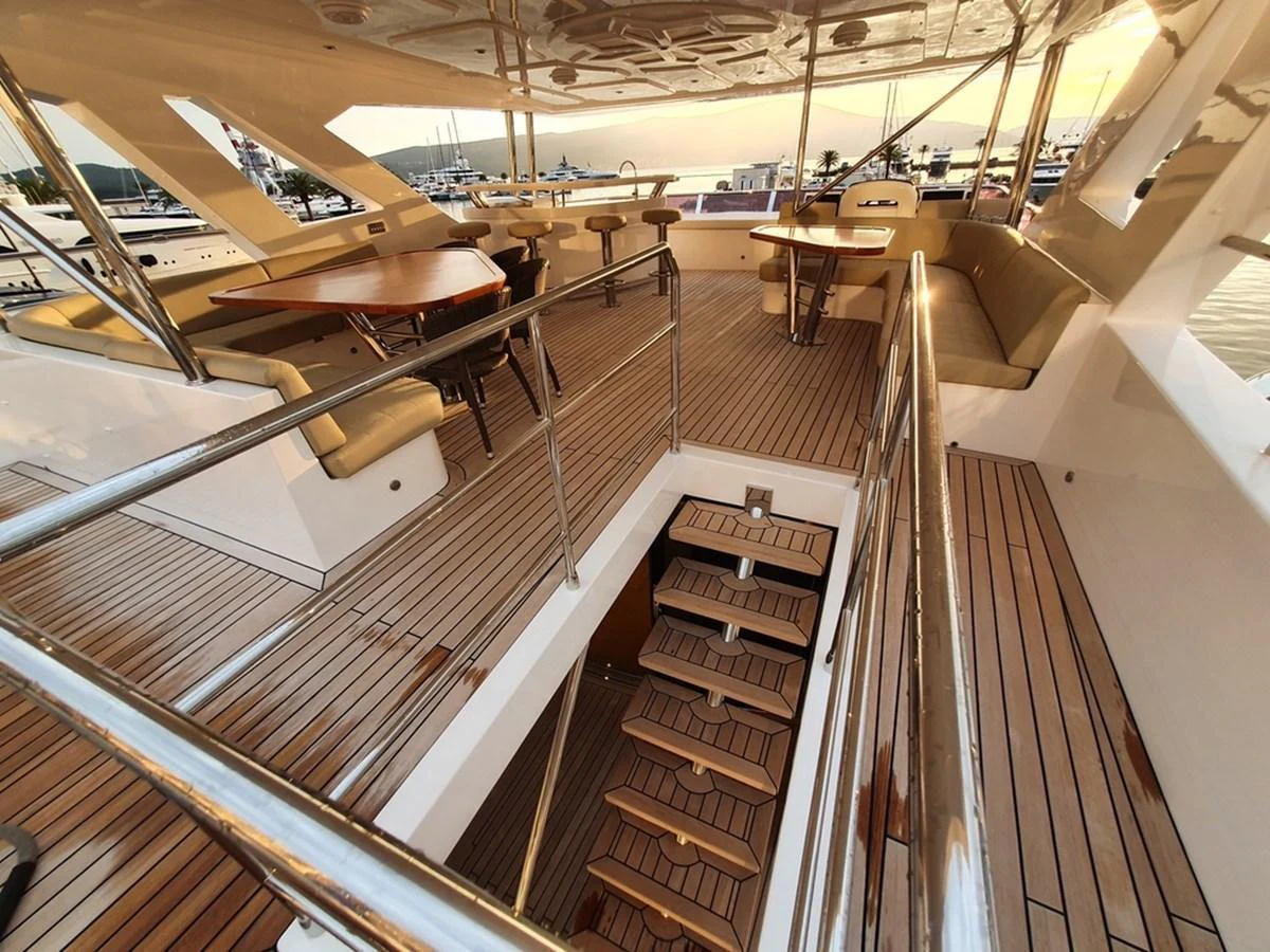 The upper deck features elegant wooden flooring, comfortable seating, and a staircase leading to the lower deck. aboard AMORE Yacht for Sale