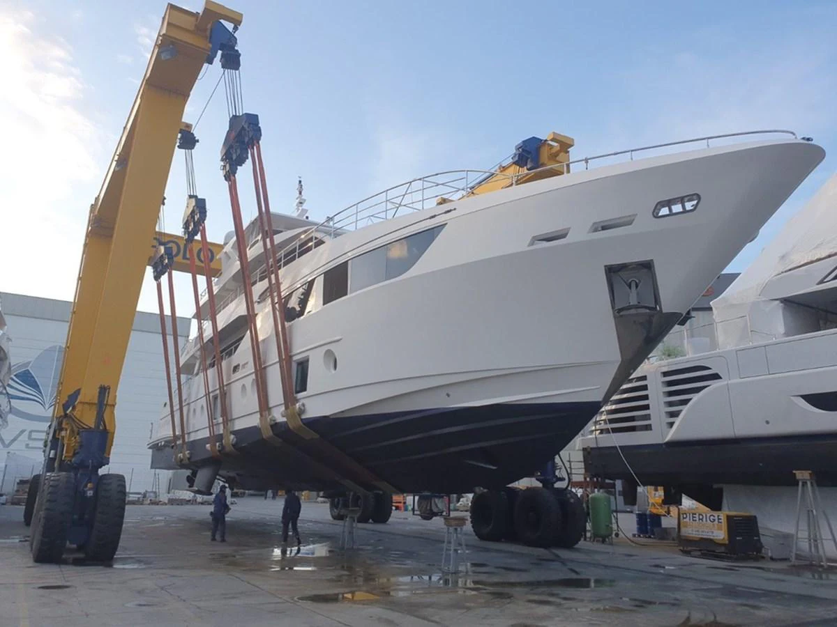 The yacht is being lifted by a crane in a shipyard, showcasing its sleek hull and modern design. aboard AMORE Yacht for Sale