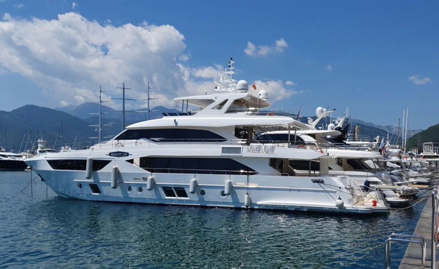 A luxurious yacht is docked at a marina under a clear blue sky. aboard AMORE Yacht for Sale