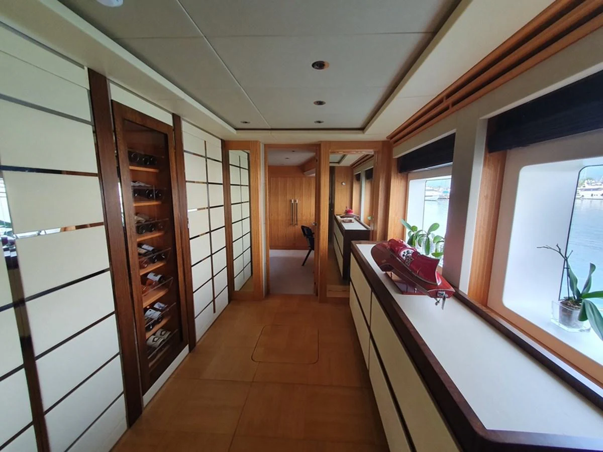 The yacht's interior features a hallway with large windows, wooden accents, and ample storage space. aboard AMORE Yacht for Sale
