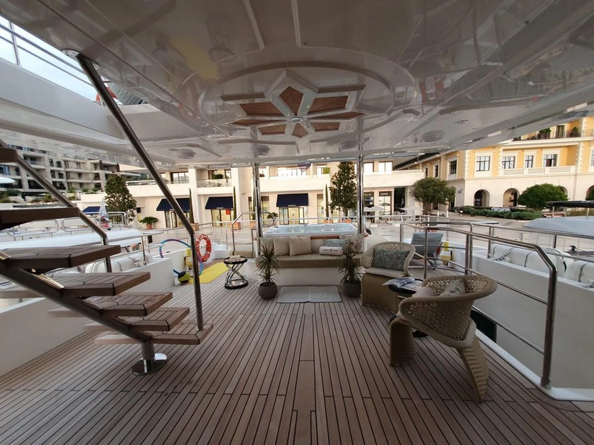The aft deck features a spacious seating area with elegant furnishings and a wooden floor. aboard AMORE Yacht for Sale