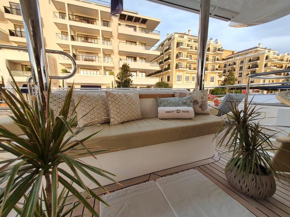 The aft deck features a comfortable seating area with plush cushions and potted plants, perfect for relaxation. aboard AMORE Yacht for Sale