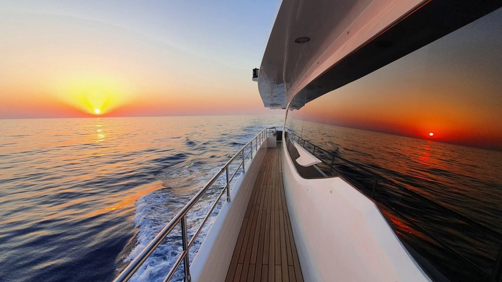 A stunning view of the yacht's side deck at sunset, reflecting the serene ocean and vibrant sky. aboard AMORE Yacht for Sale