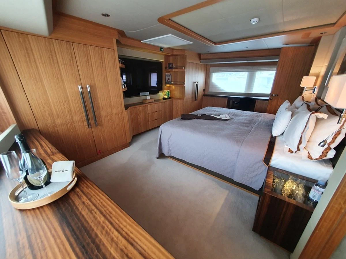 The master stateroom features a luxurious bed, ample storage, and elegant wood finishes. aboard AMORE Yacht for Sale