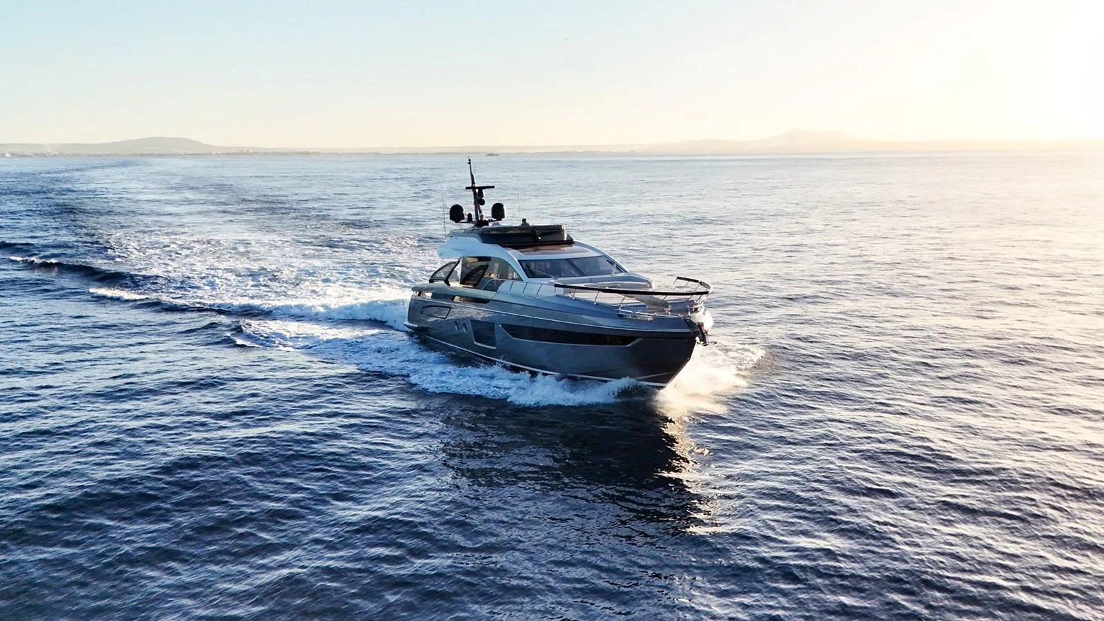 A sleek yacht cruises through calm waters at sunset, showcasing its modern design and elegance. aboard APRICITY Yacht for Sale