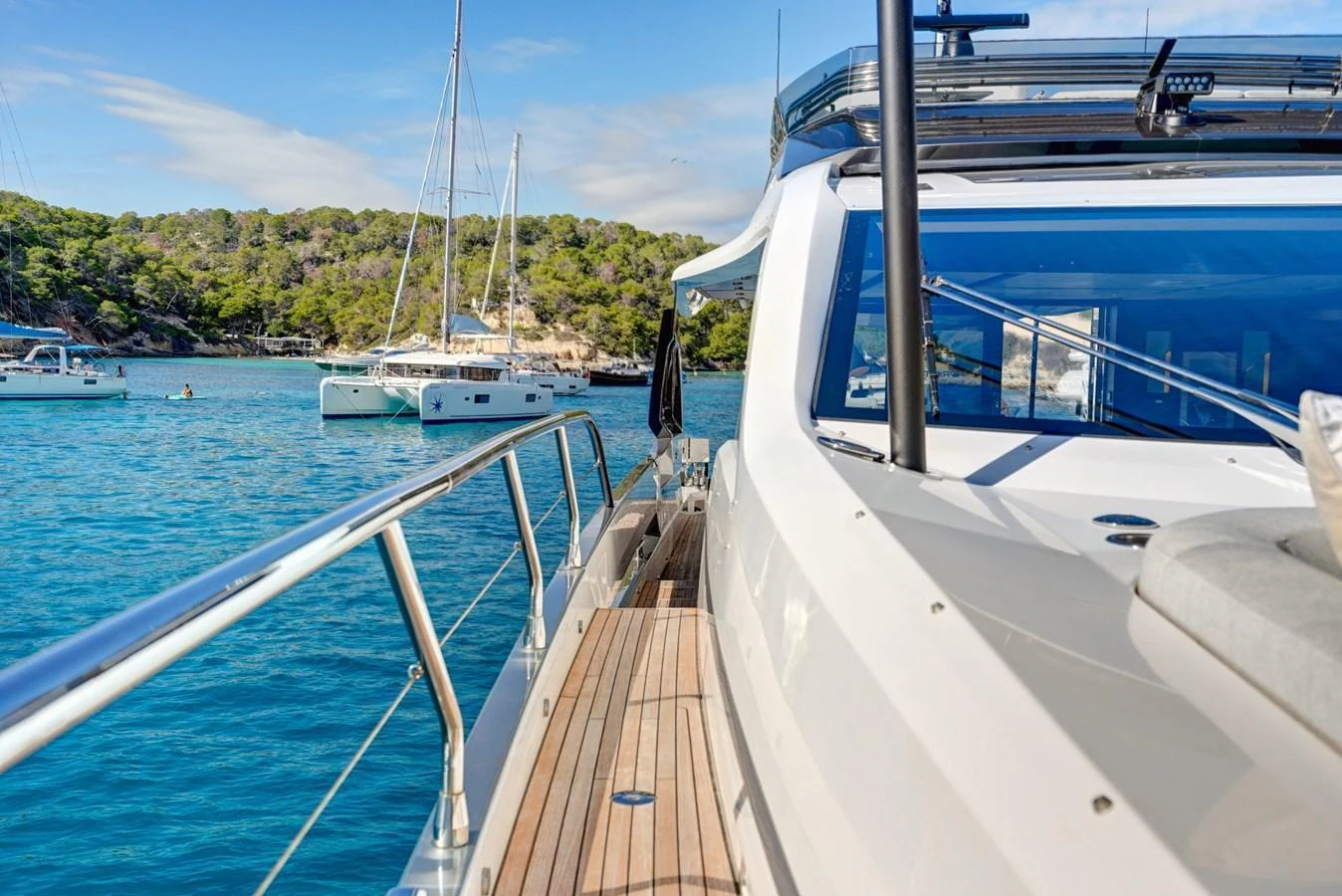 The yacht's side deck offers a stunning view of the surrounding waters and nearby anchored boats. aboard APRICITY Yacht for Sale