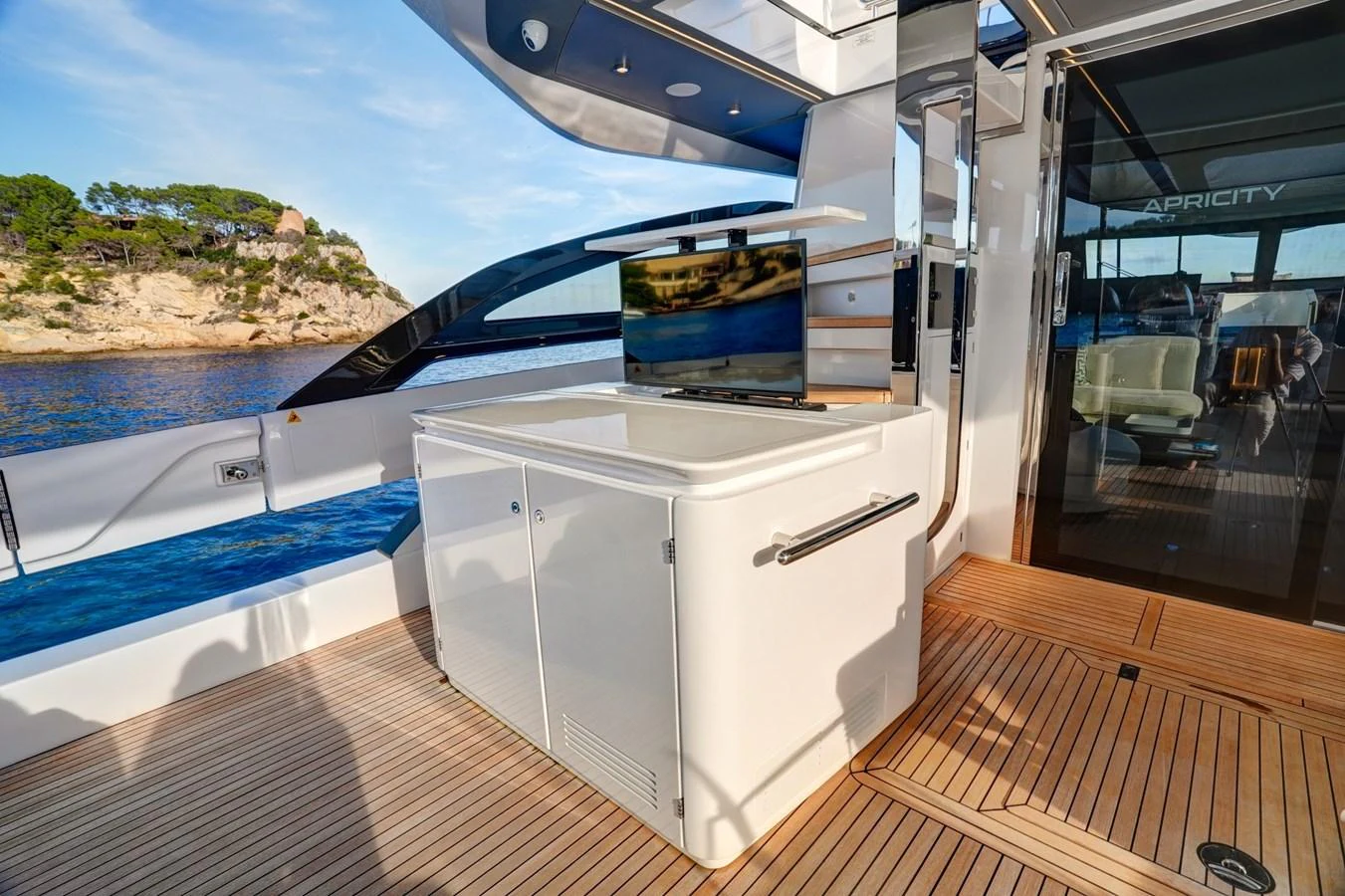 The aft deck features a sleek entertainment area with a pop-up TV and modern cabinetry. aboard APRICITY Yacht for Sale