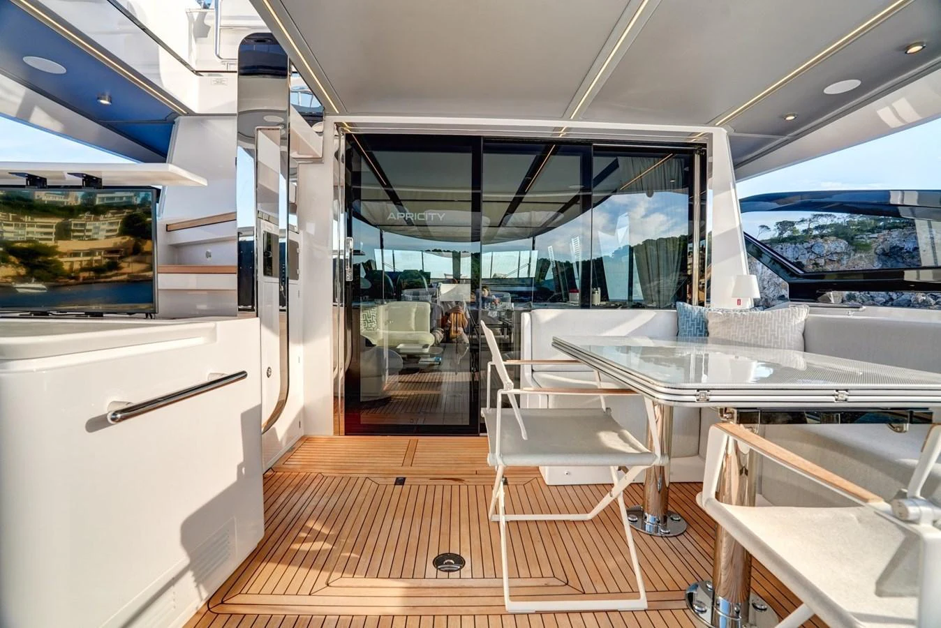 The aft deck features a comfortable seating area with a dining table, perfect for alfresco meals and relaxation. aboard APRICITY Yacht for Sale