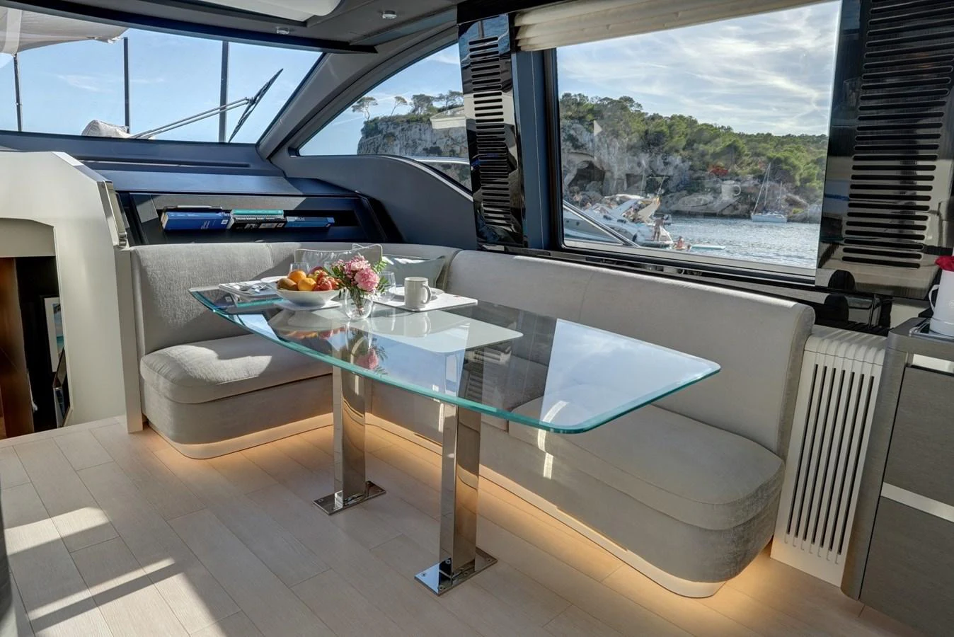 The salon features a sleek glass dining table with a comfortable seating area, offering stunning views through large windows. aboard APRICITY Yacht for Sale
