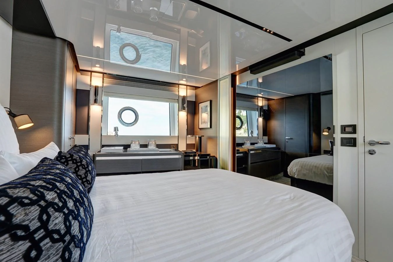 A luxurious stateroom featuring a large bed, modern decor, and ample natural light from a porthole window. aboard APRICITY Yacht for Sale