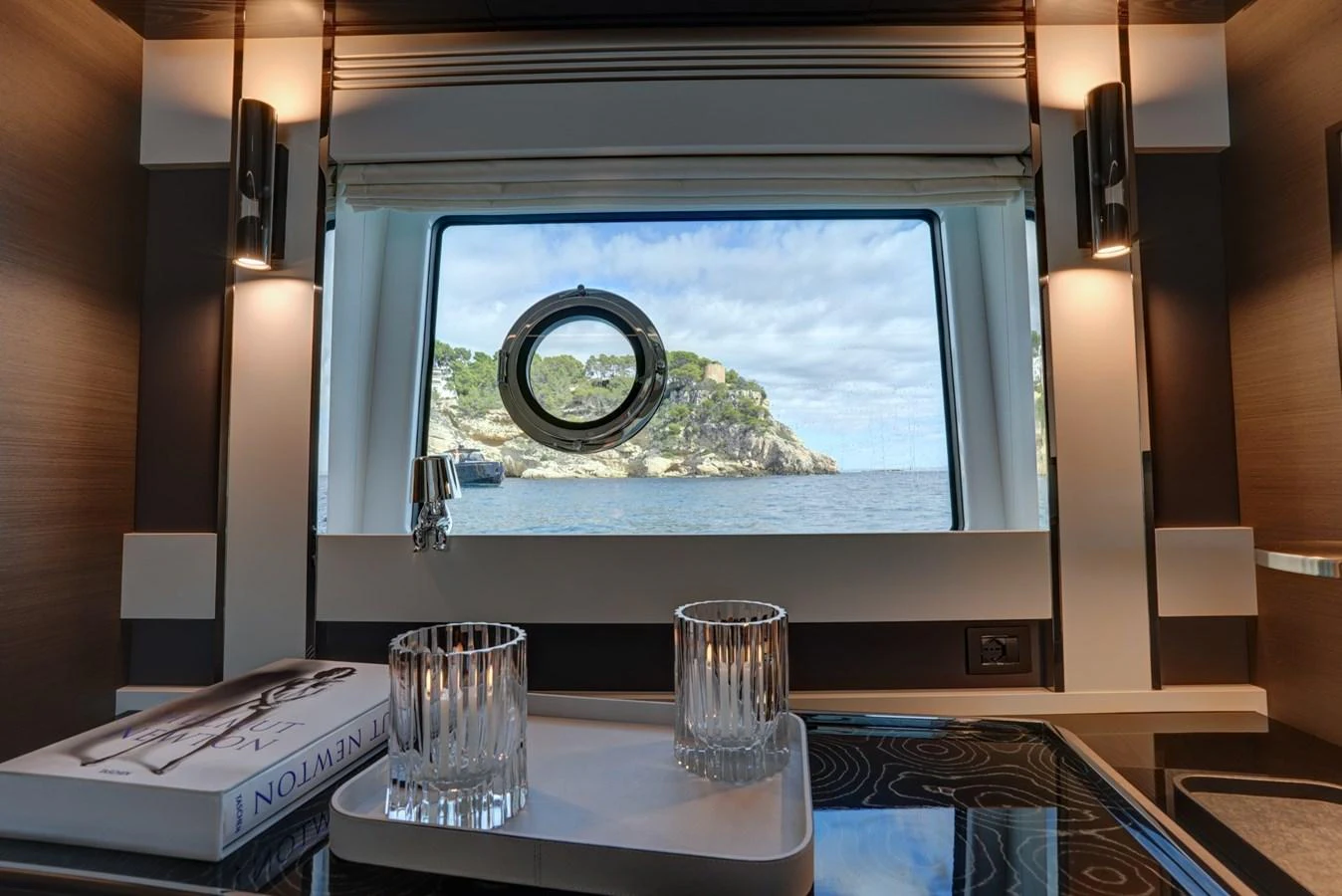 A cozy interior space with a scenic view through a porthole window. aboard APRICITY Yacht for Sale