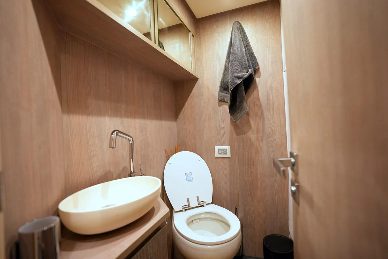 The yacht's head features a modern sink and toilet with wooden paneling. aboard APRICITY Yacht for Sale