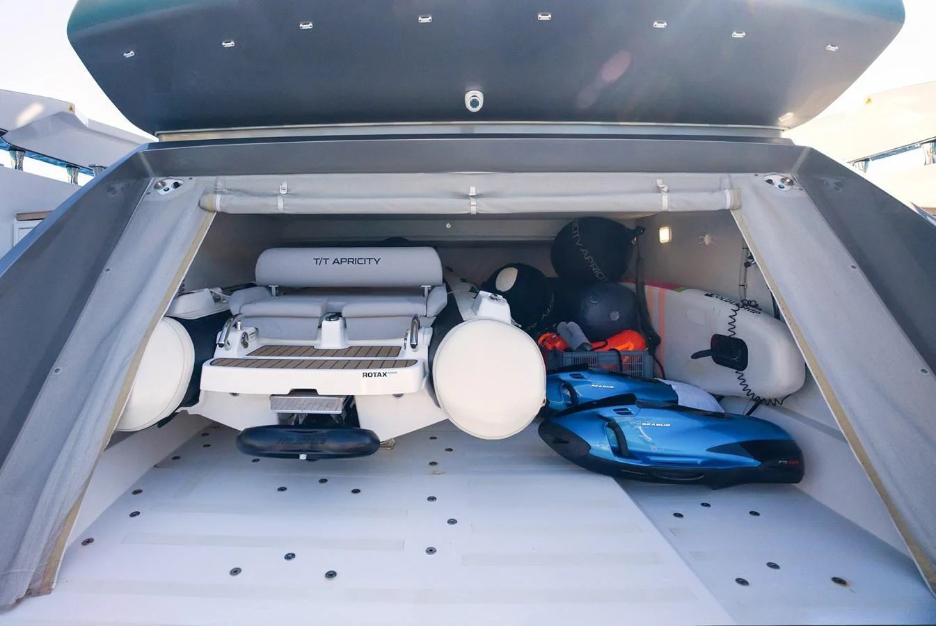The yacht's tender garage is neatly organized with a tender and various water toys. aboard APRICITY Yacht for Sale