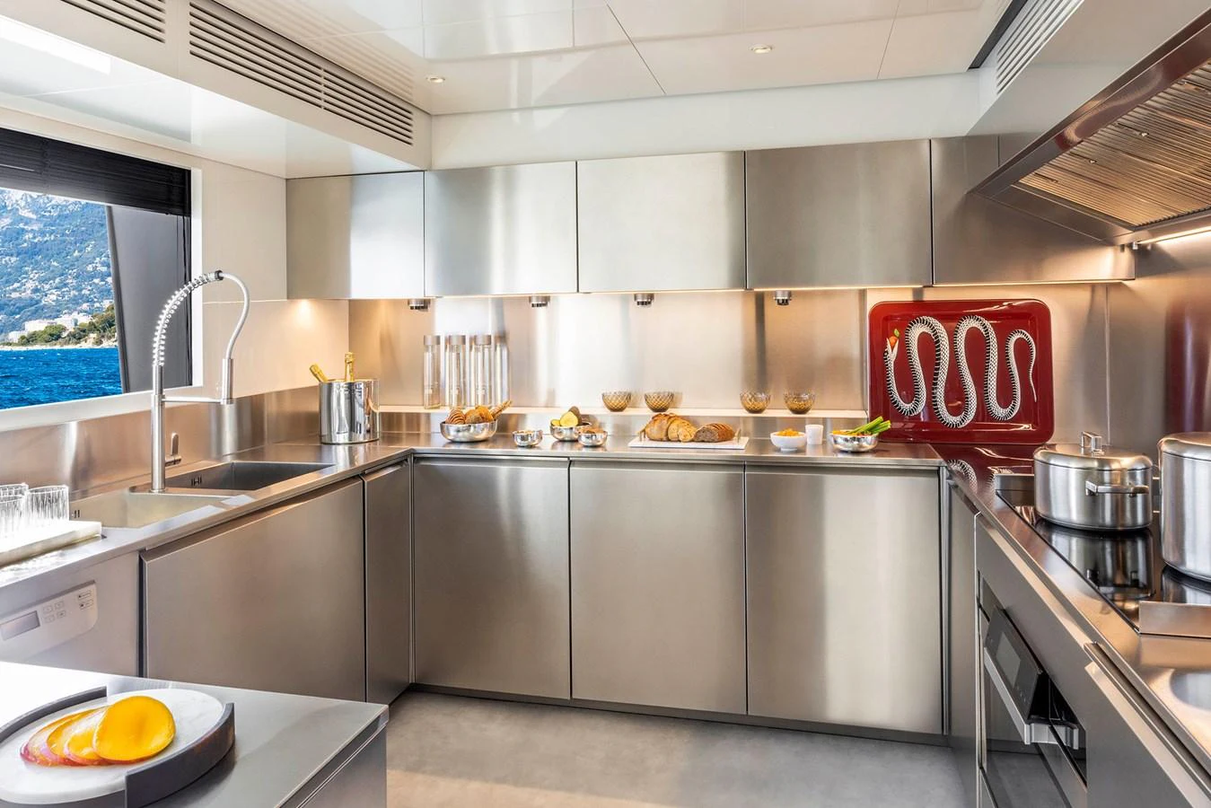 The yacht's galley features modern stainless steel appliances and a scenic window view. aboard MIOTU Yacht for Sale