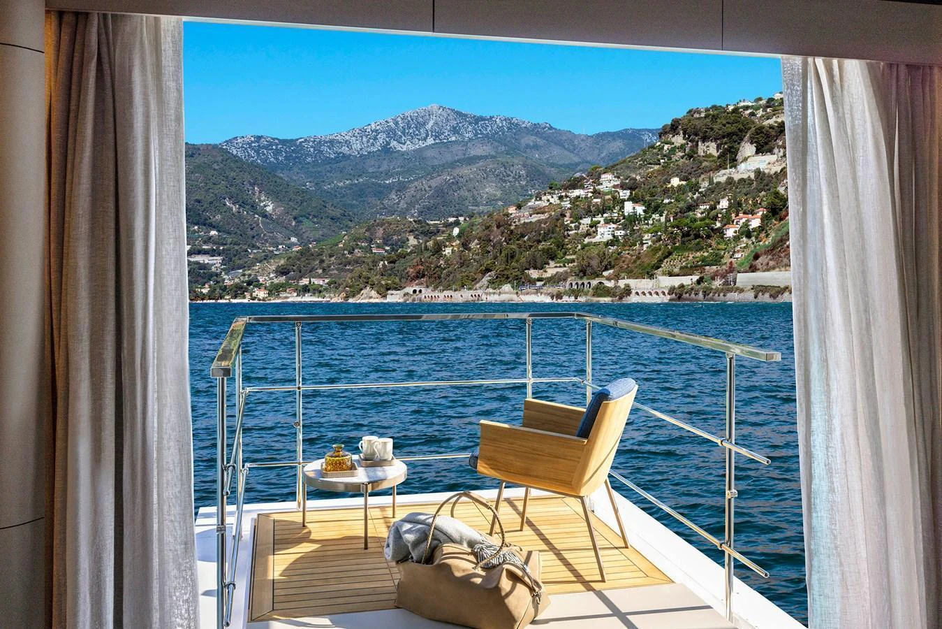 A serene aft deck with a comfortable chair and table, offering stunning views of the coastline and mountains. aboard MIOTU Yacht for Sale