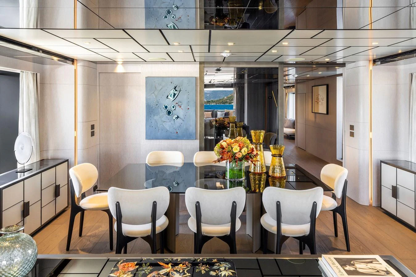 The yacht's dining area features a sleek, modern design with a glass table and elegant seating. aboard MIOTU Yacht for Sale