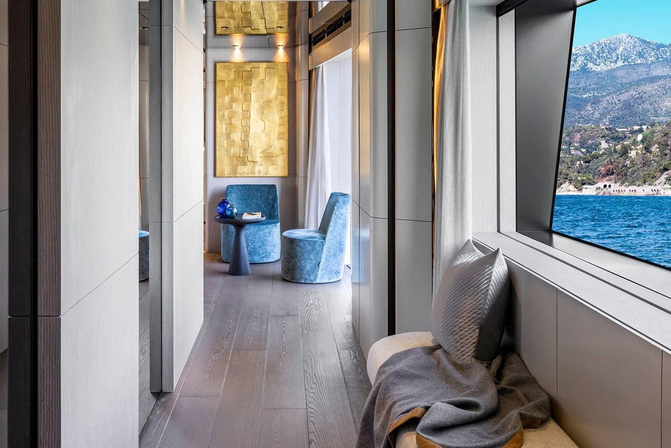 A luxurious hallway with elegant seating and a scenic view through large windows. aboard MIOTU Yacht for Sale
