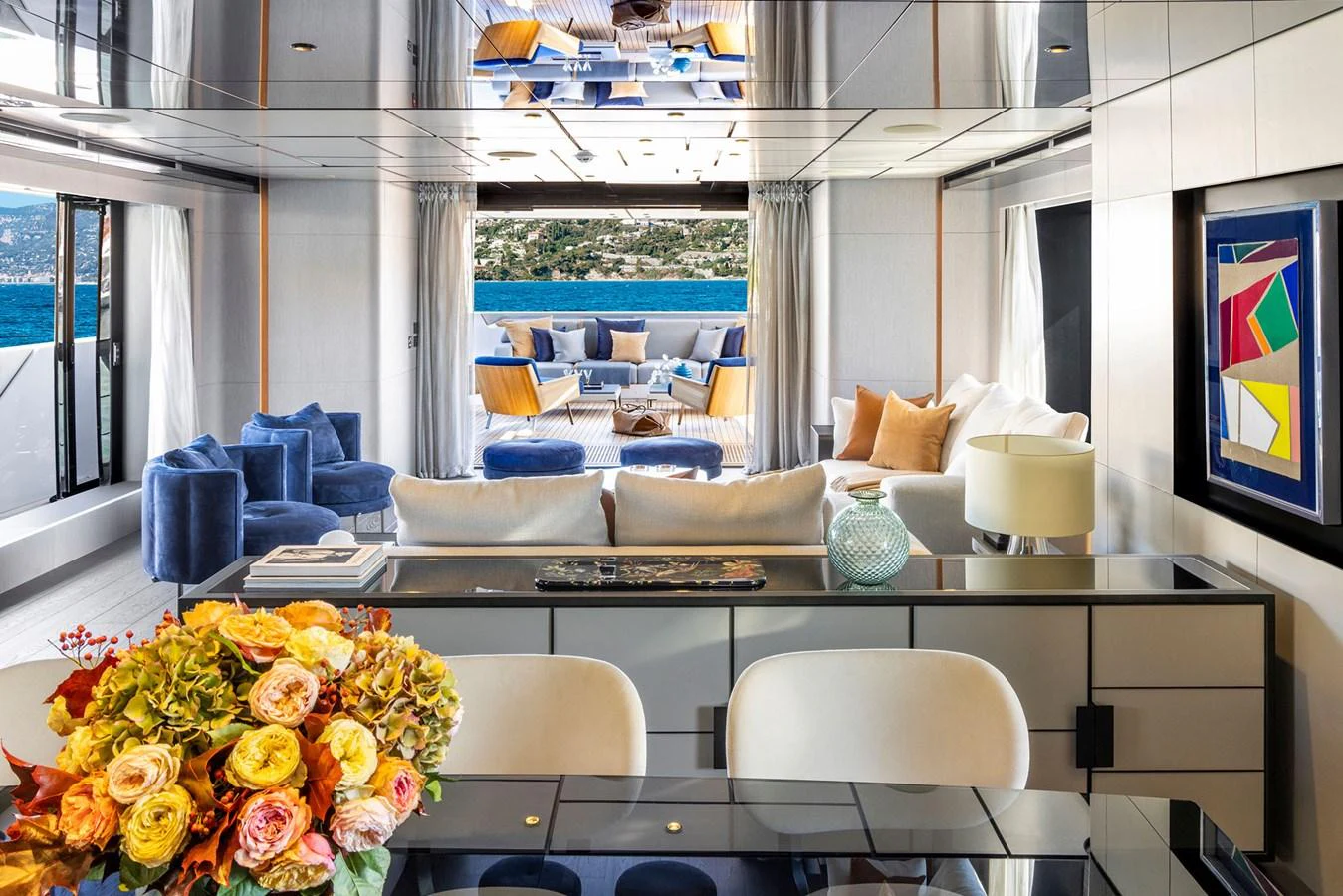 The yacht's salon features luxurious seating with a view of the aft deck and ocean beyond. aboard MIOTU Yacht for Sale