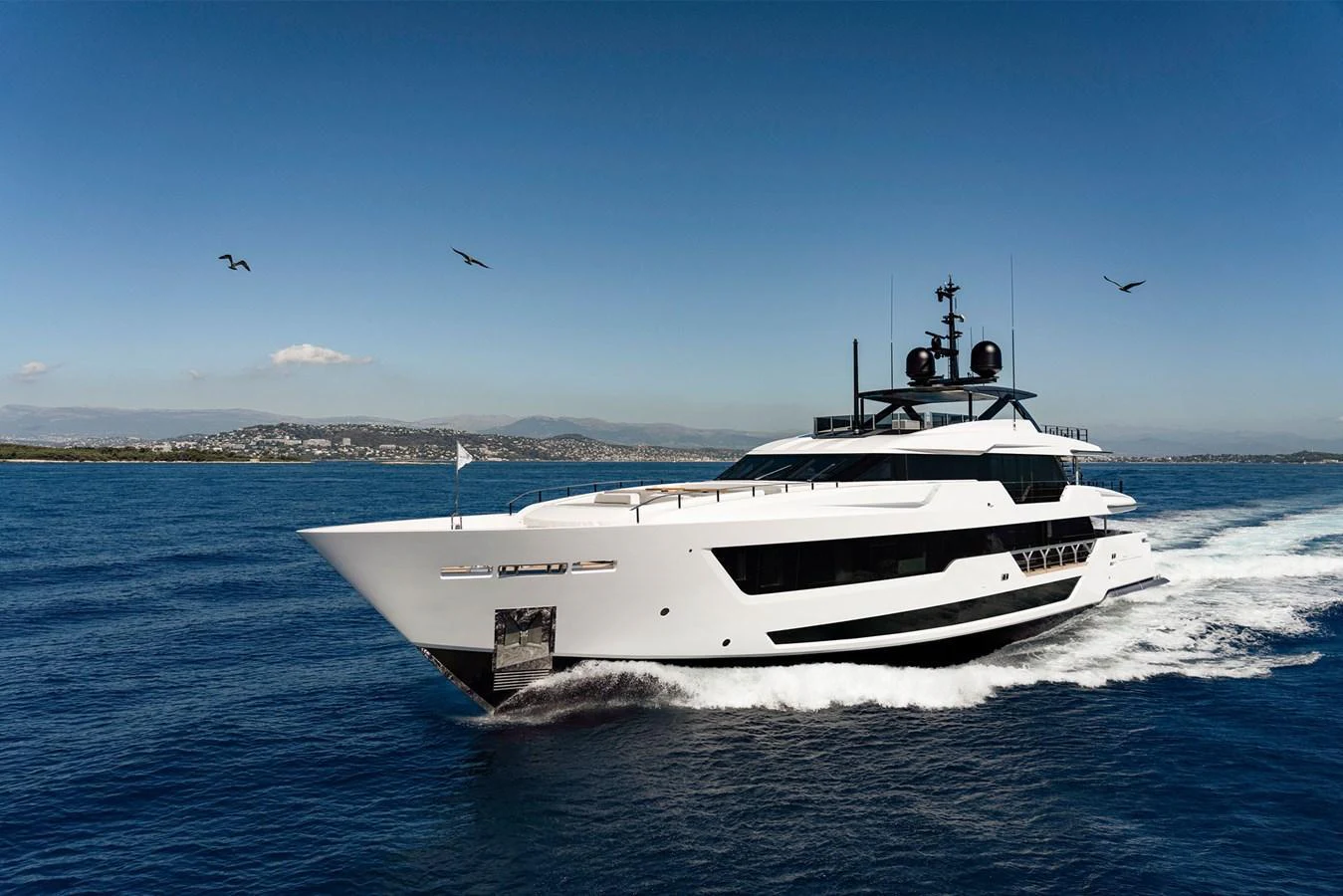 A sleek, modern yacht glides through the water under a clear blue sky. aboard MIOTU Yacht for Sale