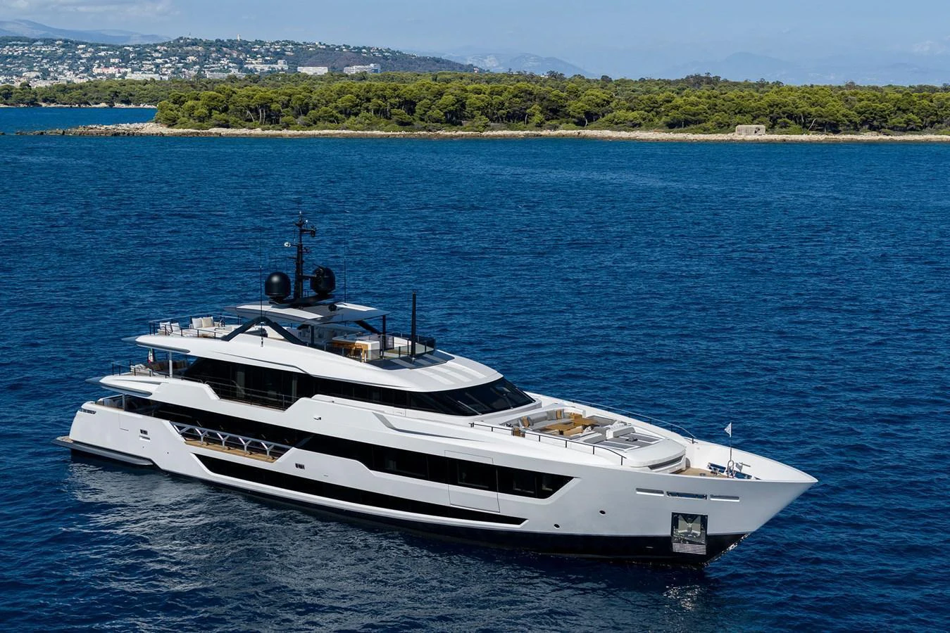A sleek and modern yacht cruises gracefully on the open water with a scenic coastline in the background. aboard MIOTU Yacht for Sale