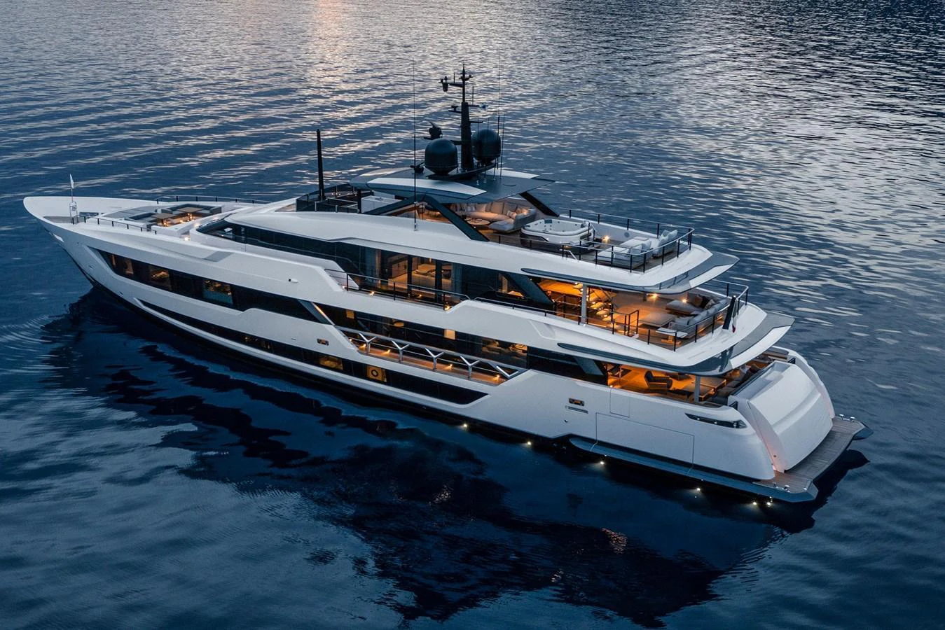 A sleek and modern yacht glides gracefully on calm waters during twilight. aboard MIOTU Yacht for Sale
