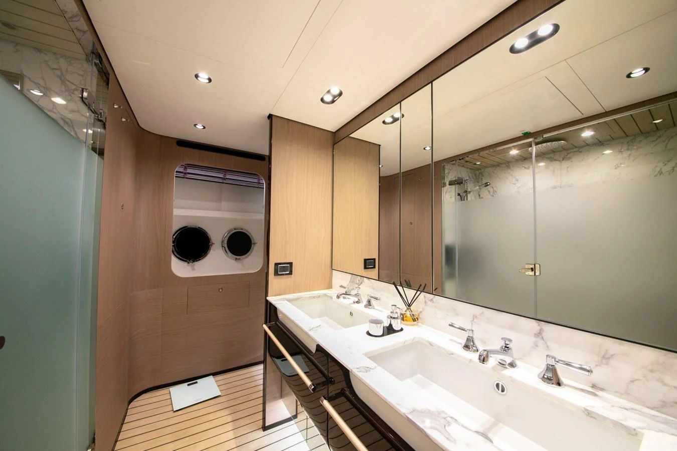 The yacht's bathroom features a double sink vanity with modern fixtures and ample lighting. aboard NIRVANA BY THE SEA Yacht for Sale